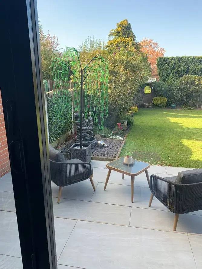 Garden seating area and water feature beside a new porcelain patio by G&M Building Solutions